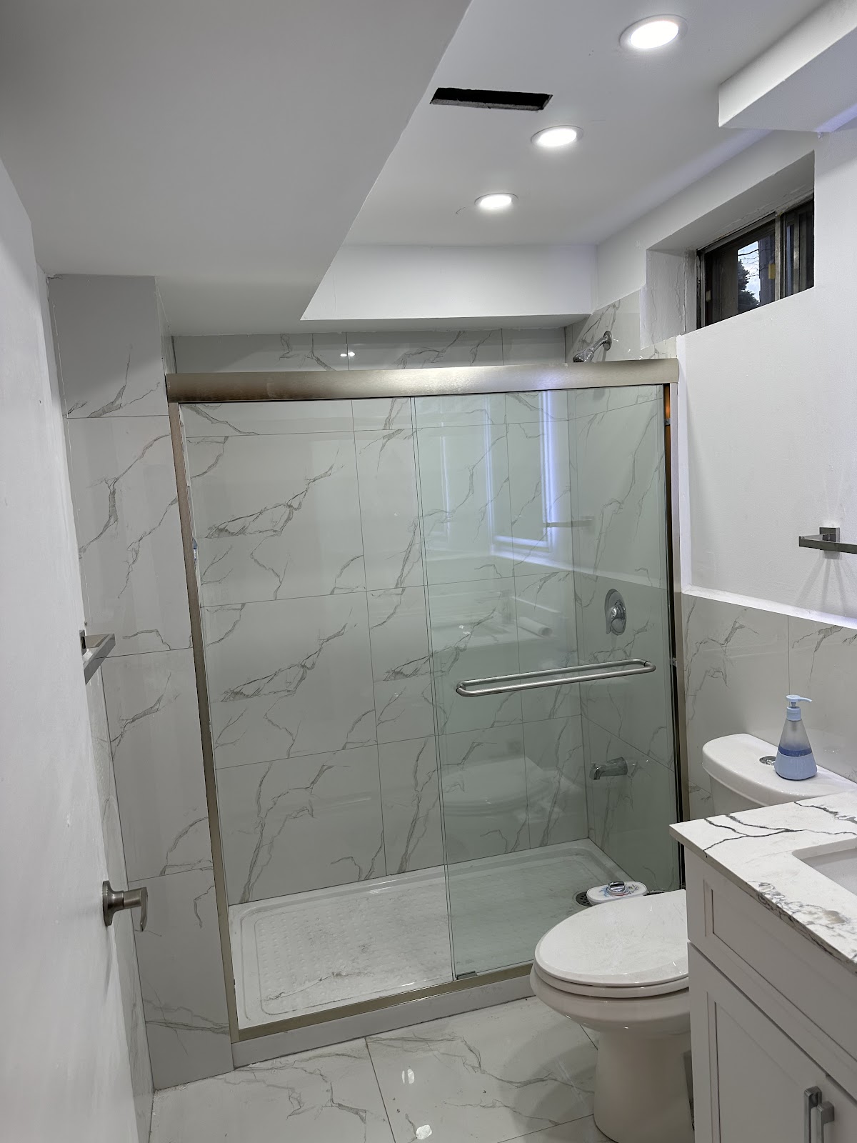 Finished bathroom with marble-look tile, glass shower enclosure, and new vanity