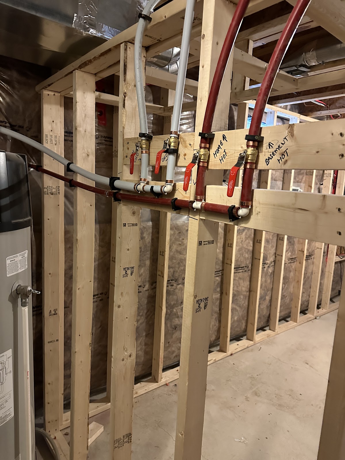 Labeled PEX water lines and shutoff valves in a new construction plumbing rough-in